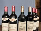 several bottles of wine are lined up on a wooden table