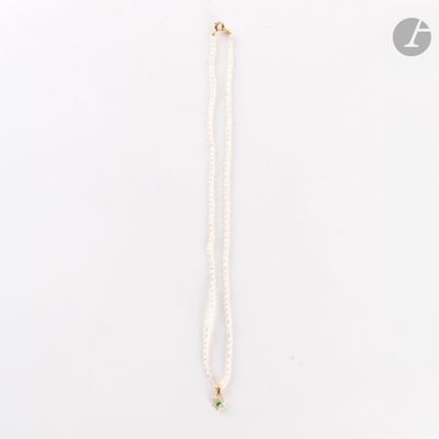 un collier blanc composé d'une chaîne dorée et d'une perle blanche