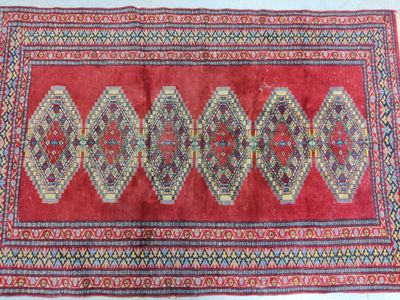 Tapis Bukhara en laine à 4 caissons sur fond rouge.