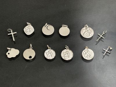 several silver charms and a cross on a black surface