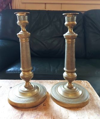 une paire de bougeoirs en laiton posés sur une table en bois devant un canapé noir