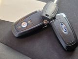 two car keys laying on the seat belt of a car