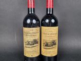 two bottles of red wine sitting next to each other on a table