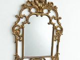 un miroir doré accroché au mur au-dessus d'un lavabo