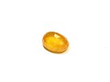 a close up of a yellow gemstone on a white surface
