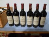six bouteilles de vin rouge sont alignées sur une table