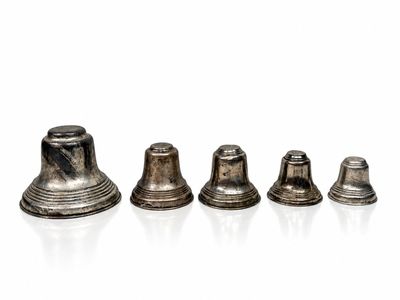 three silver bells sitting next to each other on a white surface