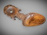 une vieille cuillère en bois au manche sculpté, posée sur une surface grise