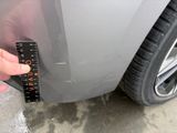 a hand that is holding a measuring tape to the side of a car