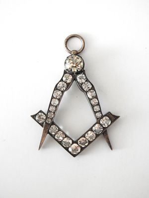 un gros plan sur un pendentif représentant une équerre et un compas maçonniques