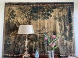 two vases and a lamp on a table in front of a tapestry