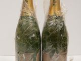 two bottles of champagne wrapped in plastic wrap on a white surface