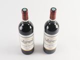 two bottles of wine sitting next to each other on a white surface