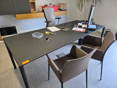 a black table with chairs and a laptop on it