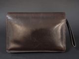 a brown leather wallet with a long strap on a black background