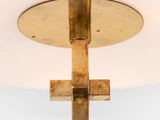 brass cross on a white ceiling with a light in the middle