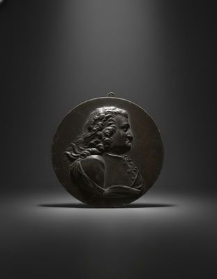 a bronze medallion of a man holding a book