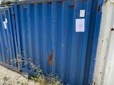 un conteneur bleu posé par terre à côté d'un bâtiment
