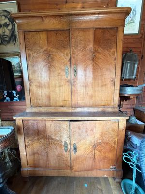 a wooden cabinet with a door on top of it in a room