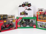 quatre modèles différents de tracteurs dans des boîtes, posés sur une surface blanche