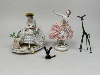 trois figurines représentant des femmes et une girafe posées sur une table