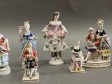 seven figurines of people dressed in different costumes