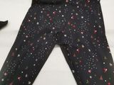 black leggings with christmas trees and stars on them on a bed