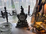 une table sur laquelle se trouvent une horloge et des bougies, près d'une fenêtre
