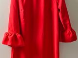 a red dress hanging on a hanger against a white wall