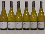 six bottles of white wine are lined up on a table