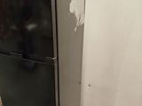 a black refrigerator sitting in the corner of a room