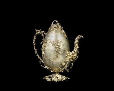 an image of a silver teapot on a stand with a black background