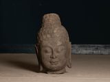 statue of a head of a buddha sitting on a wooden floor