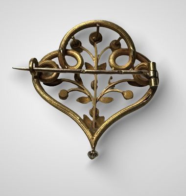 une broche en or représentant des feuilles et des fleurs sur fond blanc
