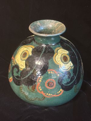 un vase vert orné d'un motif sur fond noir