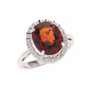gros plan d'une bague avec une pierre rouge entourée de diamants