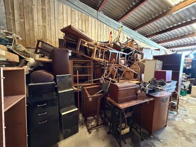 un tas de vieux meubles dans un garage rempli de bric-à-brac