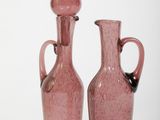 two pink vases sitting next to each other on a white surface