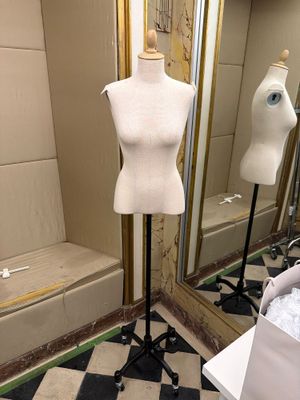 un mannequin assis sur un socle dans une pièce