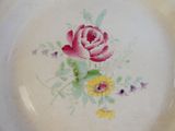 une assiette blanche décorée d'une rose rose et de fleurs jaunes