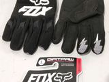des gants et des autocollants Fox Racing posés sur une table, à côté d'un téléphone