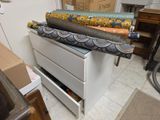 Plusieurs rouleaux de tissu sont posés sur un tiroir dans une pièce.