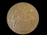 gold medal depicting a man on horseback and a woman on a horse