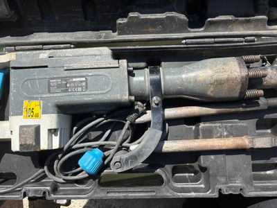 une perceuse et d'autres outils rangés dans une mallette posée par terre