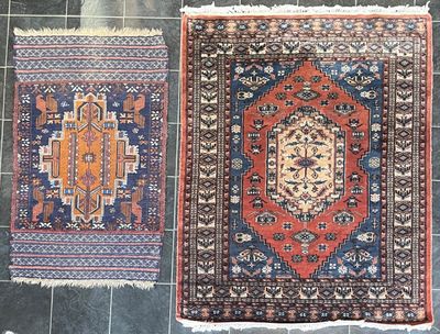 deux tapis orientaux posés sur un sol carrelé, avec un chat assis par terre