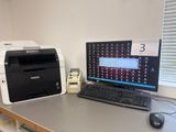 un ordinateur et une imprimante posés sur un bureau dans une pièce