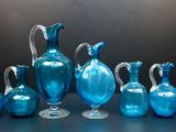 Plusieurs vases en verre bleu sont alignés sur une table
