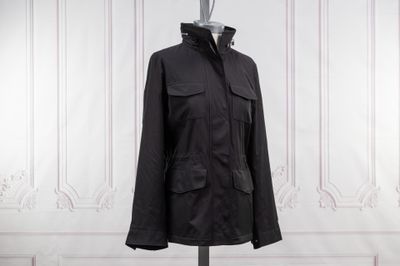 black jacket on a mannequin stand in front of a white wall