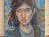 painting of a woman ' s face on a shelf in front of a white wall