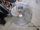a fan that is sitting on the ground next to a motorcycle